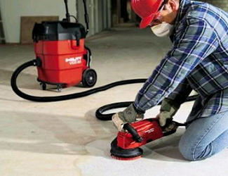 Man cleaning concrete floor with handheld floor scrubber