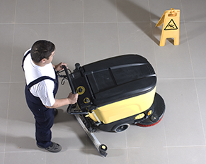 Man pushing automatic floor cleaning machine